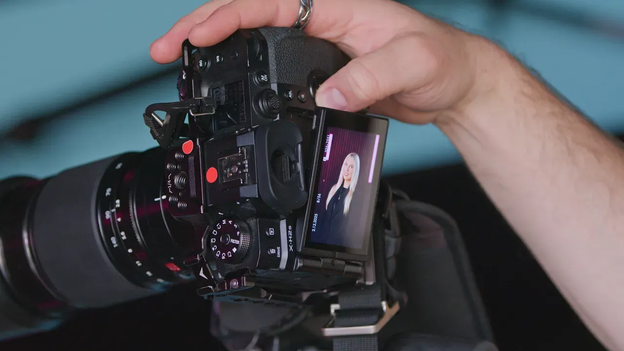 Hands holding a camera with a portrait on the screen.