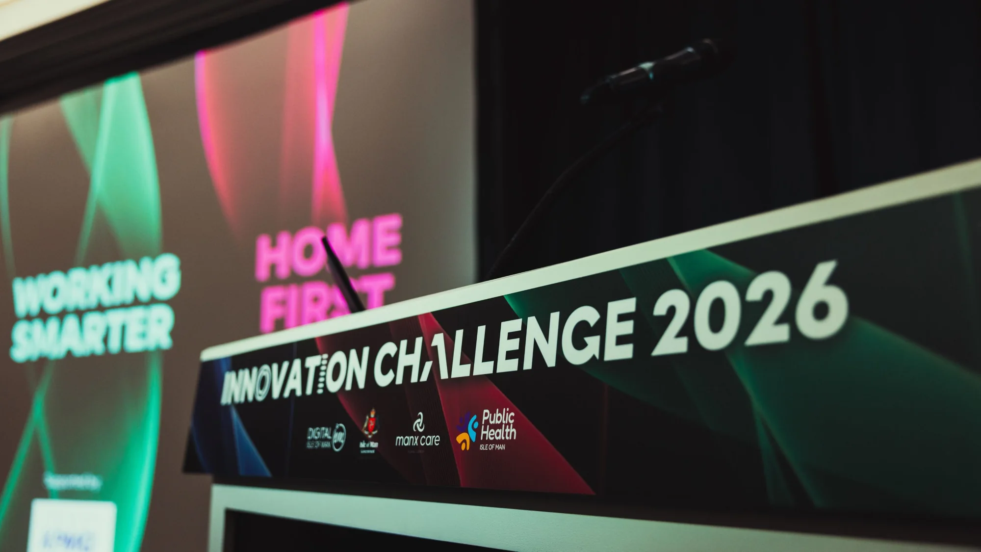 The Innovation Challenge 2026 lectern, with the Working Smarter and Home First screens behind