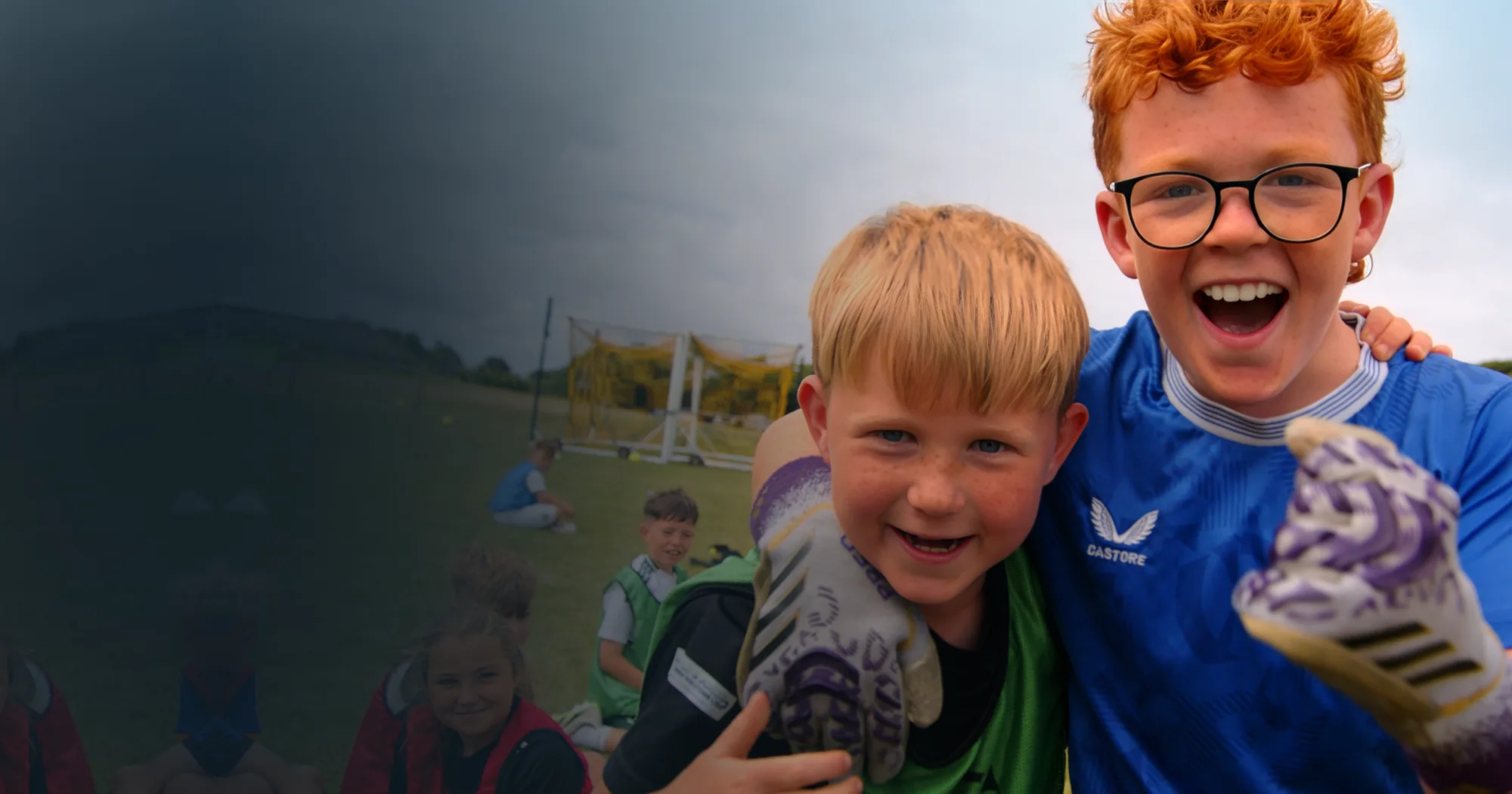 Two young players at a Let’s Play summer camp, one in a blue shirt and glasses, laughing at the camera