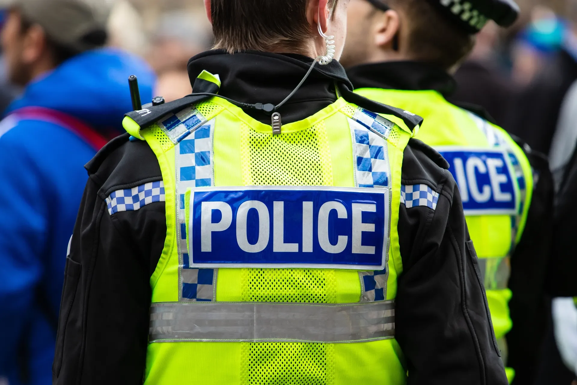 Two police officers in high-visibility jackets on duty, seen from behind