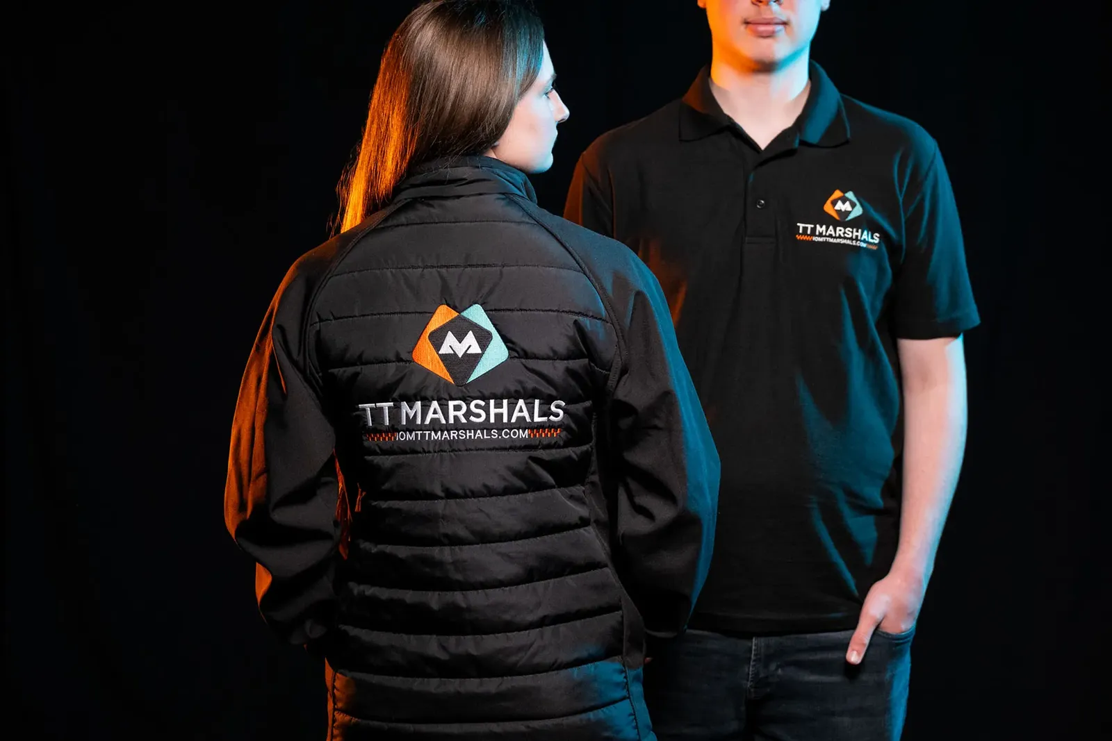 Caitlin Hampson with her back to the camera showing the TT Marshals jacket, Deane Corlett-Aspell facing the camera in the polo shirt
