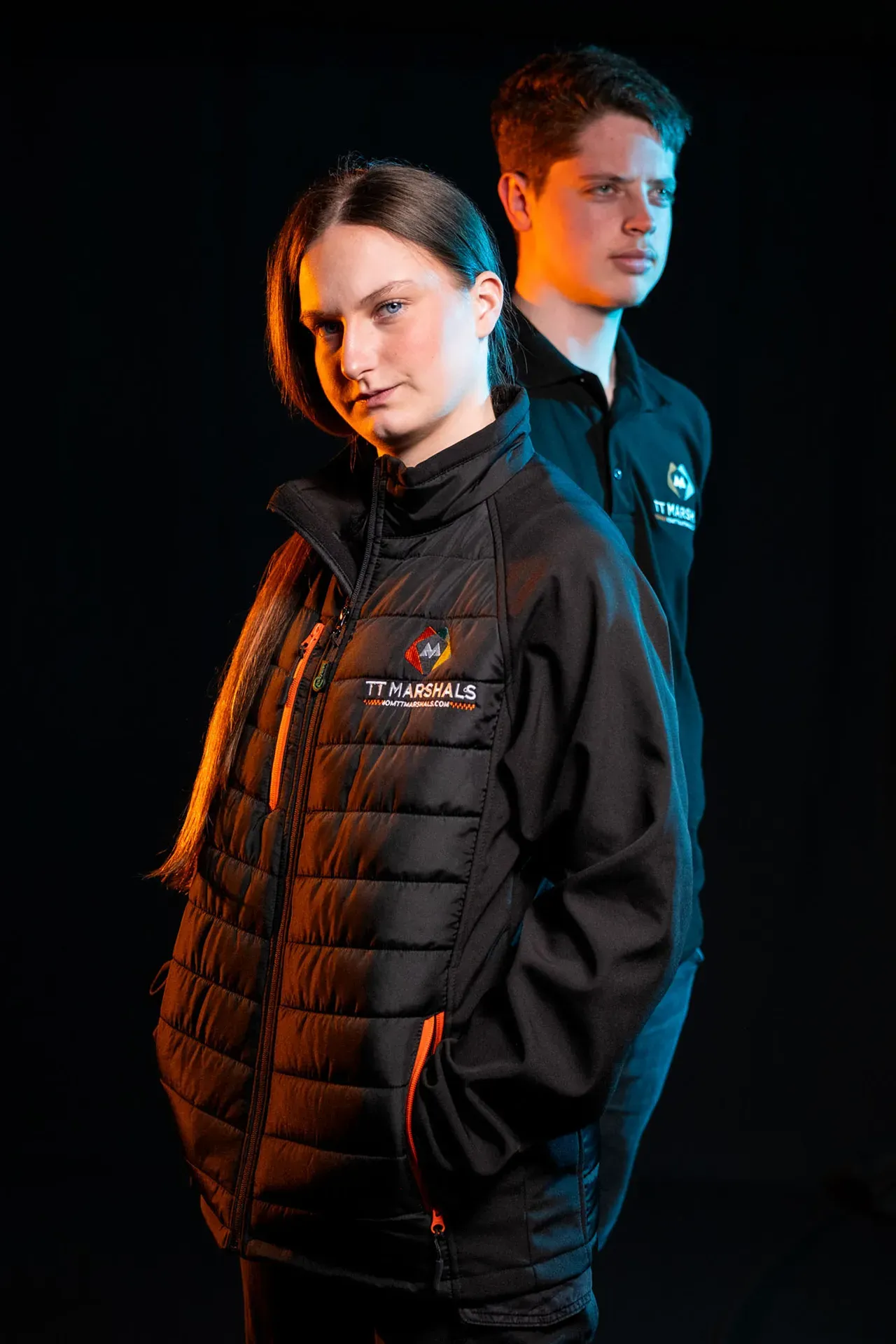 Caitlin Hampson and Deane Corlett-Aspell wearing the TT Marshals softshell padded jacket and polo shirt