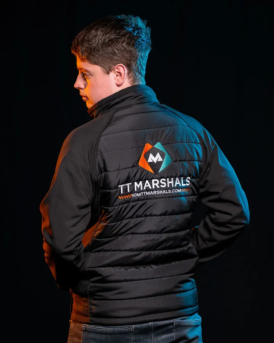 Deane Corlett-Aspell with his back to the camera showing the TT Marshals softshell jacket