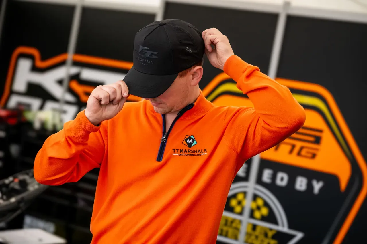 Dom Herbertson adjusting his cap in his racing marquee, wearing the TT Marshals prize jumper