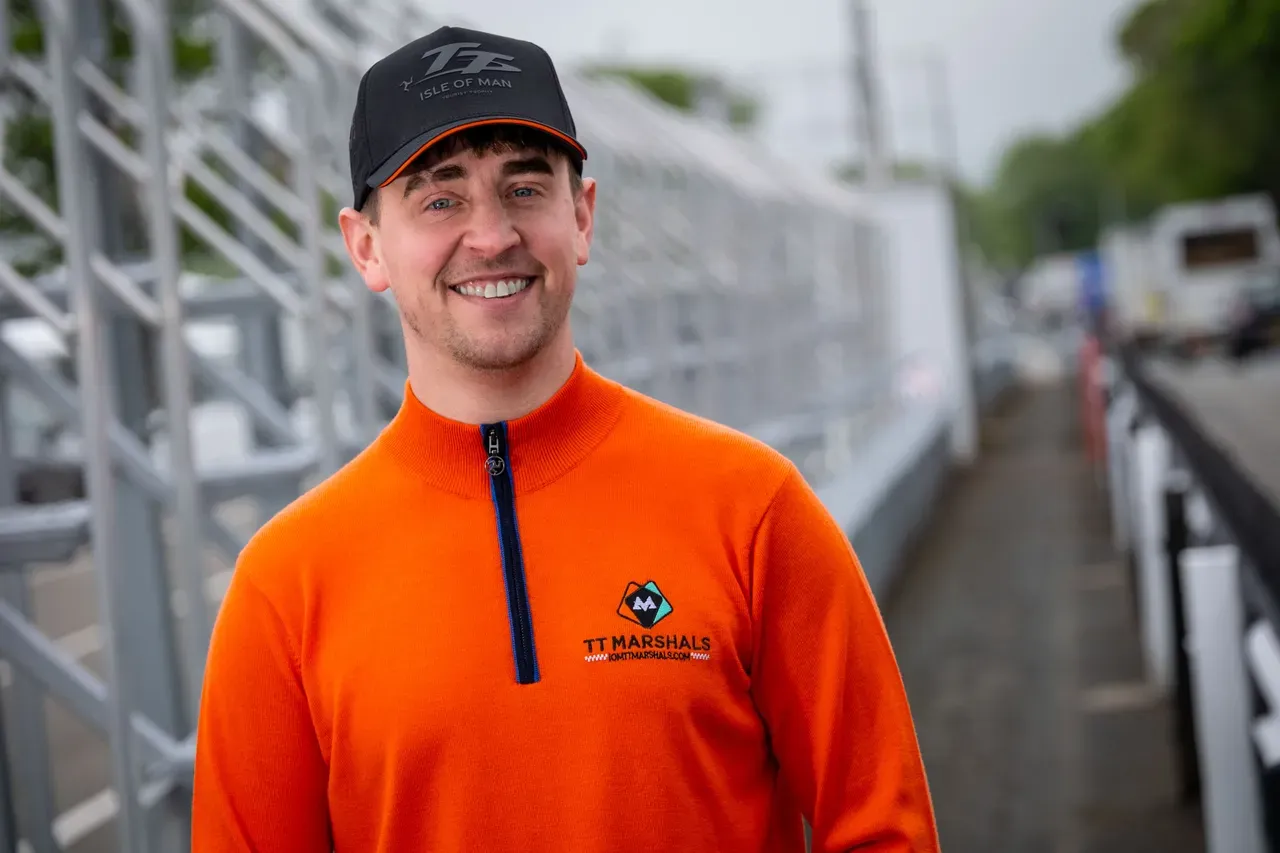 Dom Herbertson smiling by the pit lane railings in the TT Marshals prize jumper